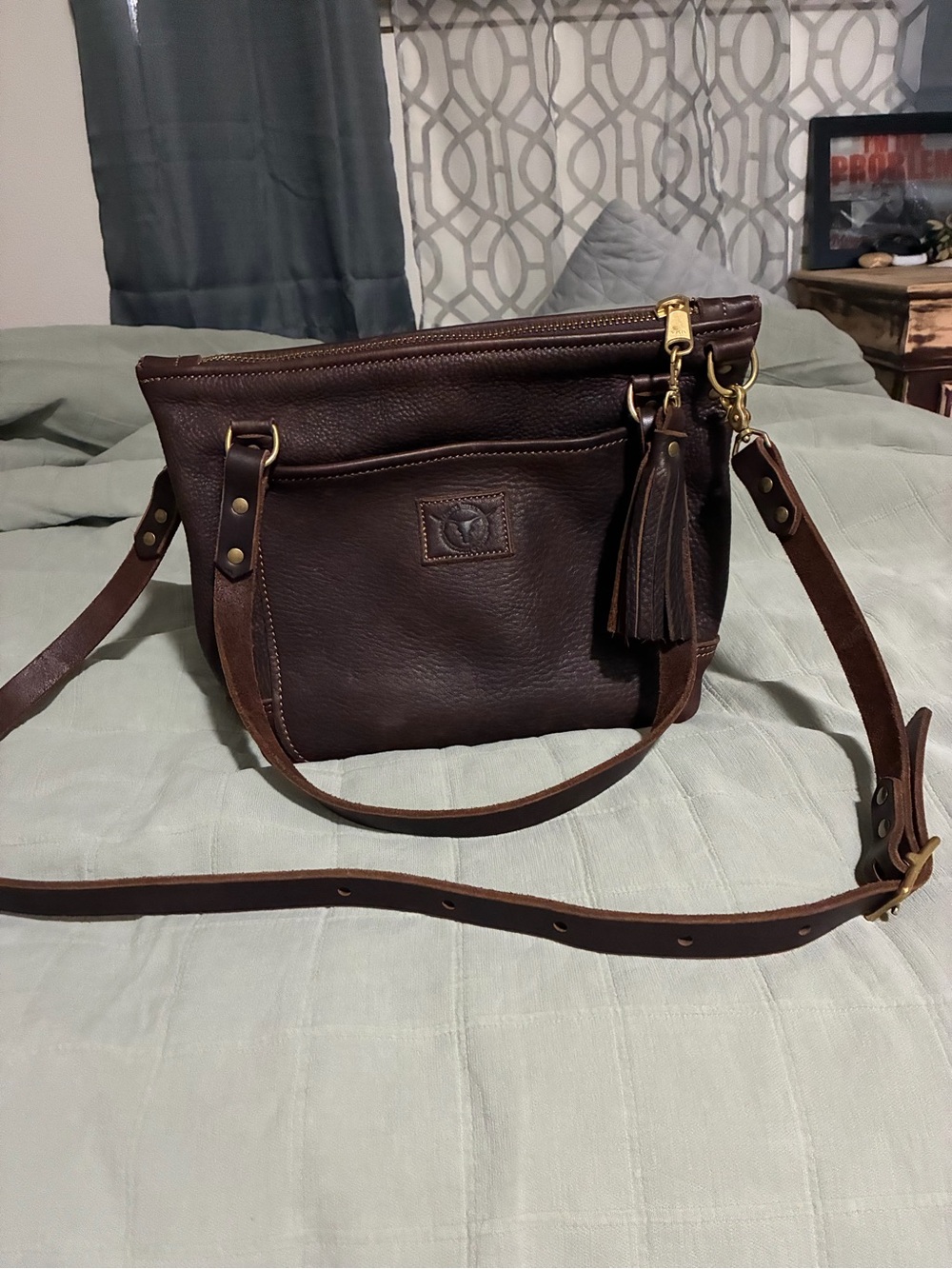 Dark Brown Leather Crossbody Bag with Tassel Accent. The color is Texas Tea